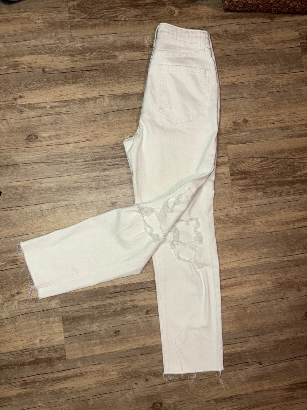 Ripped white denim jeans with a stacked button fly closure.